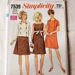 Puede incluir: Patrón de costura Simplicity vintage con tres diseños de vestidos. La portada del patrón muestra ilustraciones de los vestidos en marrón y naranja, con una chaqueta blanca. El patrón incluye el texto "7539", "Junior Size 9", y "Contorno de busto 81 cm".