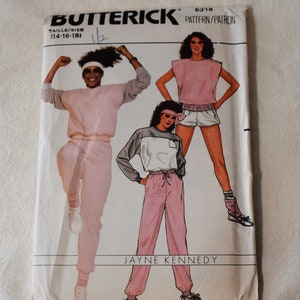 May include: A vintage Butterick sewing pattern, featuring illustrations of athletic wear. The pattern includes designs for a pink and gray tracksuit, shorts, and a top. The text on the pattern reads "Butterick" and "Jayne Kennedy".
