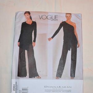 Puede incluir: Patrón de costura Vogue Patterns con dos conjuntos negros. El patrón incluye un top de manga larga y pantalones de pernera ancha, y un top de un solo hombro con pantalones de pernera ancha. El patrón es de Donna Karan, una diseñadora americana de Vogue. El número de patrón es 2064.