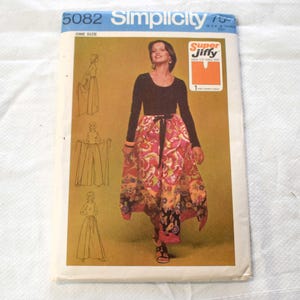 May include: A vintage Simplicity sewing pattern envelope, featuring a woman modeling a long-sleeved black top and a colorful patterned skirt. The envelope is labeled "5082" and "Super Jiffy". The pattern is one size.