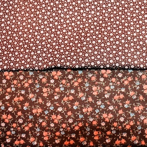 May include: Two fabric swatches. The top swatch is a dark brown with a pattern of small white dots. The bottom swatch is dark brown with a floral pattern of pink, blue, and white flowers.
