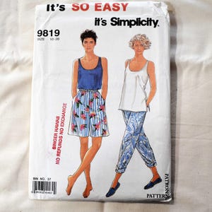 Puede incluir: Un paquete de patrones de costura Simplicity vintage. El paquete presenta ilustraciones de dos conjuntos: una camiseta sin mangas azul con pantalones cortos florales y una camiseta sin mangas blanca con pantalones estampados. El texto incluye "It's SO EASY" y "it's Simplicity."
