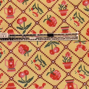 K&ouml;nnte beinhalten: Gelber Stoff mit einem sich wiederholenden Muster aus roten Kirschen, roten Erdbeeren, roten H&auml;hnen, roten Teekannen und roten Topfpflanzen. Der Stoff wird mit einem Lineal gemessen, auf dem "DRITZ Sewing Gauge" steht.