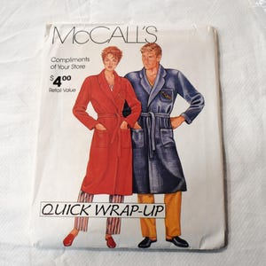 May include: A McCall's sewing pattern envelope titled QUICK WRAP-UP featuring illustrations of two individuals wearing belted robes. One robe is solid red, and the other is dark blue with a chest pocket. The envelope includes text and pricing.