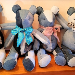 May include: Four denim teddy bears with different colored bows. The bears are made from recycled denim and have a patchwork design.