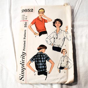 May include: Simplicity sewing pattern number 2652 for a blouse. The pattern is for a miss size 16, bust 36. The pattern shows three different styles of blouses, one with a red collar, one with a white collar, and one with a plaid collar.
