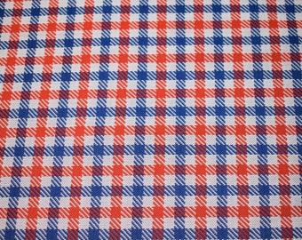 May include: Red and blue checkered fabric with a white background. The fabric has a woven texture.