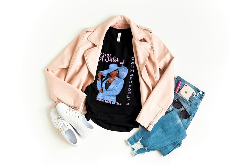 May include: A black t-shirt with a graphic of a woman wearing a blue suit and a hat. The text on the shirt reads "A Sister of Gamma Phi Delta Unique Since 1943".