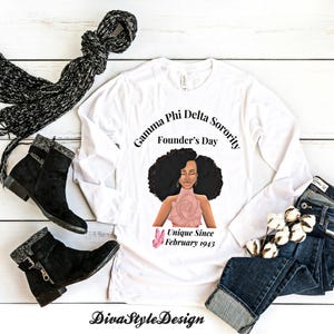 Peut inclure: Un t-shirt blanc à manches longues avec un graphisme de femme et le texte "Gamma Phi Delta Sorority Founder's Day Unique Since February 1943." L'image comprend également des bottes noires, une écharpe noire et un jean bleu.