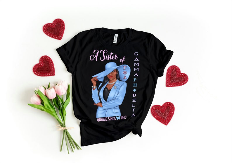 May include: Black t-shirt with a graphic of a woman wearing a blue suit and a hat. The text "A Sister of Gamma Phi Delta" and "Unique Since 1943" is printed on the shirt.