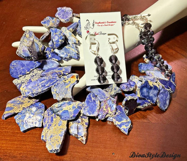 Puede incluir: Un collar de declaraci&oacute;n azul y dorado hecho de piedras grandes de forma irregular. El collar se combina con un brazalete de cristal negro y pendientes a juego. Los pendientes son de estilo colgante con tres cuentas de cristal negro.