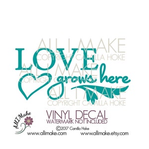 May include: Teal vinyl decal with the text "Love grows here" and a heart shape. The decal is designed for use on a wall or other surface.