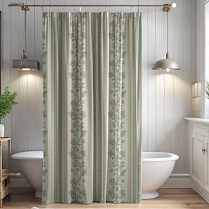 May include: A shower curtain featuring a vertical pattern of sage green floral vines alternating with thin stripes in shades of cream, beige, and muted green. The fabric hangs from a metal rod with visible rings, displaying a pleated drape.