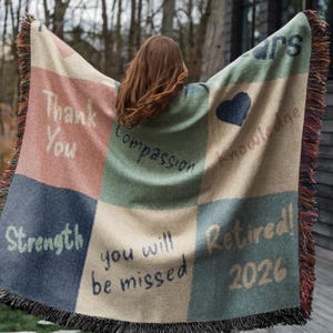 Puede incluir: Una manta tejida con un diseño de retazos en tonos azules, verdes, beige y rosa. La manta presenta las palabras "Thank You", "Strength", "Compassion", "Knowledge", "You will be missed" y "Retired! 2026". Tiene un borde con flecos.