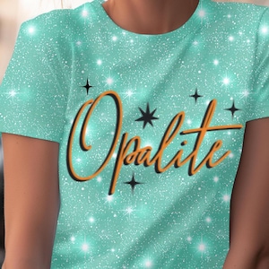 Pode incluir: Uma camiseta turquesa com efeito brilhante e a palavra "Opalite" em fonte laranja. A camiseta tem gola redonda e é decorada com estrelas pretas e brilhos brancos.