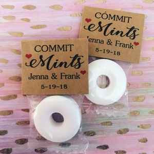 May include: Two small brown paper bags with white mints inside. The bags have a heart and the text "COMMIT eMINTS Jenna & Frank 5-19-18" printed on them.
