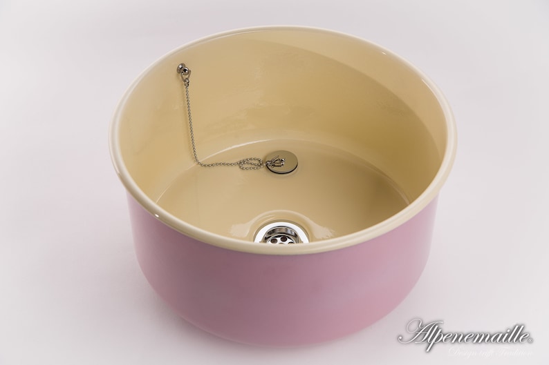 K&ouml;nnte beinhalten: Ein rosa Keramiksp&uuml;le mit cremefarbenem Innenraum. Die Sp&uuml;le hat einen Abfluss mit einer Kette und einem Stopfen.
