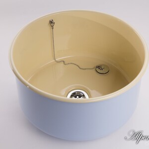 K&ouml;nnte beinhalten: Ein hellblaues Keramik-K&uuml;chensp&uuml;lbecken mit cremefarbenem Innenraum. Das Sp&uuml;lbecken hat einen Abfluss und eine Kette, die an einem Stopfen befestigt ist.