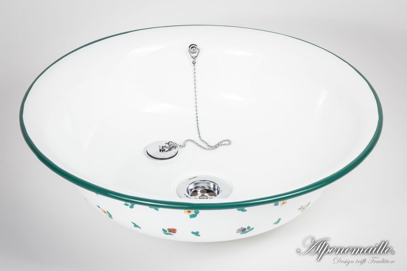May include: White enamel sink with a green rim and a floral pattern. The sink has a chrome drain stopper with a chain.