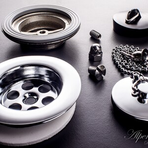 May include: A chrome sink drain with a white rubber gasket, a black rubber stopper, a chrome stopper with a chain, and two screws and a nut.