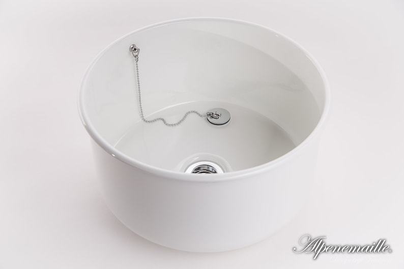 K&ouml;nnte beinhalten: Wei&szlig;e Keramiksp&uuml;le mit einem verchromten Abflussstopfen und einer Kette. Die Sp&uuml;le ist rund und hat eine glatte, gl&auml;nzende Oberfl&auml;che.