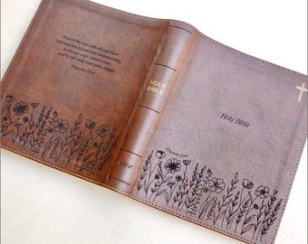 May include: Open brown leather Bible cover with floral and text details. The cover features the words "Holy Bible" and a cross. The inside cover has a floral design and the text "Trust in the Lord with all your heart..."