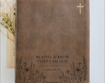 May include: Brown leather Bible cover with the text "BE STILL & KNOW THAT I AM GOD" and "psalm 46:10". Features a floral design and a cross. The name "Rachel Marie" is also printed on the cover.