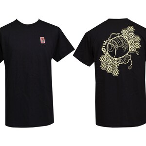 Peut inclure: T-shirt noir avec un motif dor&eacute; au dos. Le motif repr&eacute;sente une image stylis&eacute;e d'un poisson avec des motifs g&eacute;om&eacute;triques.