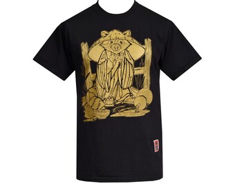 May include: Black t-shirt with a gold graphic of a raccoon wearing a hat and holding a bowl. The raccoon is sitting on a wooden fence with a bowl of food in front of it.