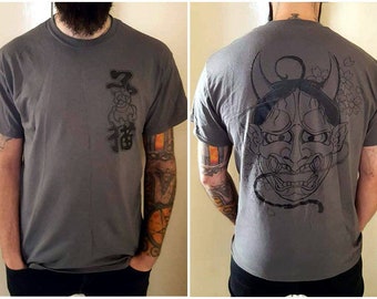 May include: A gray t-shirt with a black Japanese character design on the front and a black and white illustration of a Japanese demon on the back.