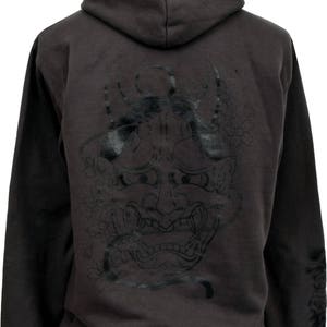 May include: A dark gray hooded sweatshirt with a black and white Japanese demon mask design on the back. The mask has a fierce expression with sharp teeth and horns.
