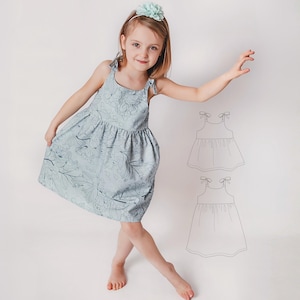 以下が含まれることがあります： 水色の花柄ドレス、結びストラップ付き。 ドレスはギャザーのスカートとシンプルなボディスが特徴です。 お揃いの花のヘッドバンドがルックを完成させます。 ドレスのスケッチが画像の右側にあります。