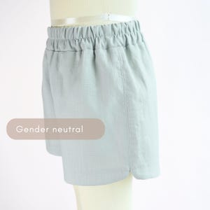 Puede incluir: Shorts de color azul claro con cintura el&aacute;stica. Los shorts tienen un corte holgado y un dobladillo curvo. El texto "Gender neutral" se muestra en un &oacute;valo marr&oacute;n claro.