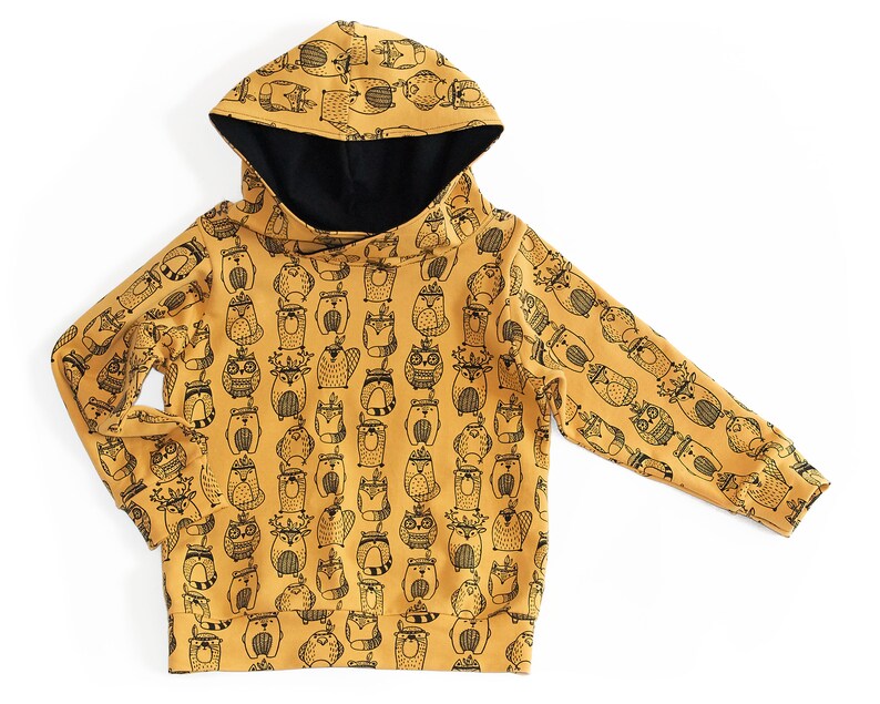 May include: A mustard yellow hooded sweatshirt with a black and white print of various woodland animals. The animals include owls, raccoons, foxes, and deer.