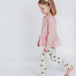 Girl modeling long-sleeve peplum top made from beginner-friendly sewing pattern for toddlers and kids