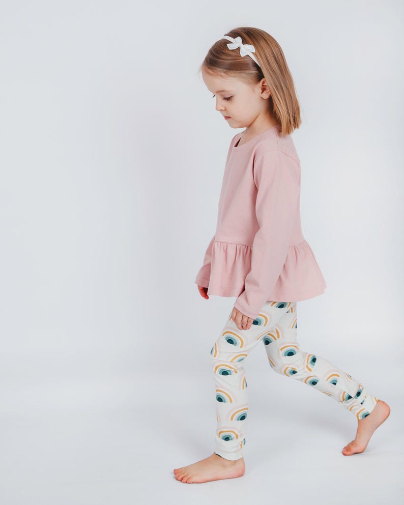 Girl modeling long-sleeve peplum top made from beginner-friendly sewing pattern for toddlers and kids