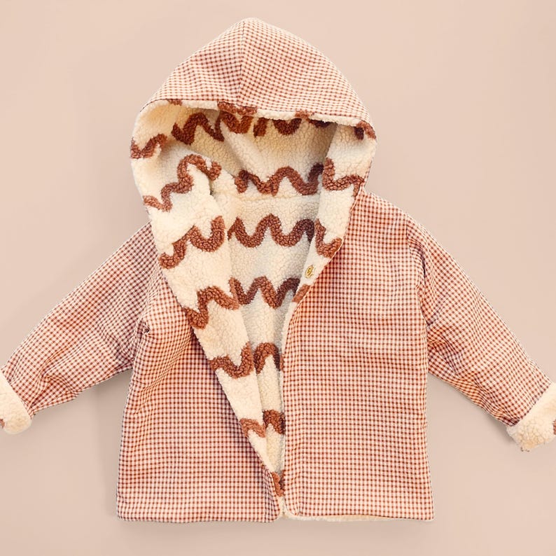 Puede incluir: Chaqueta con capucha para ni&ntilde;os con un estampado de cuadros rojos y blancos en el exterior. El interior es de material crema y esponjoso con dise&ntilde;os ondulados marrones. La chaqueta tiene cierre de bot&oacute;n y pu&ntilde;os esponjosos.