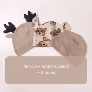 May include: Three baby hats including one solid beige hat with black knit antlers, one cream hat with a brown bear face pattern and small ears, and one solid beige hat. Text on the image reads: RECOMMENDED FABRICS Knit fabric.