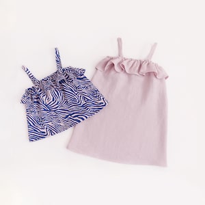 Op de afbeelding: Twee mouwloze tops. Eén is lichtpaars met een gerimpelde halslijn. De andere is een blauw-witte zebraprint met een gerimpelde halslijn. Beide tops hebben dunne bandjes.