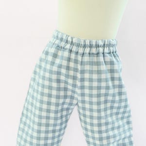 May include: Light blue and white gingham patterned pajama pants with an elastic waistband. The pants are made of a soft fabric and are designed for comfort. The classic check pattern is a timeless design.