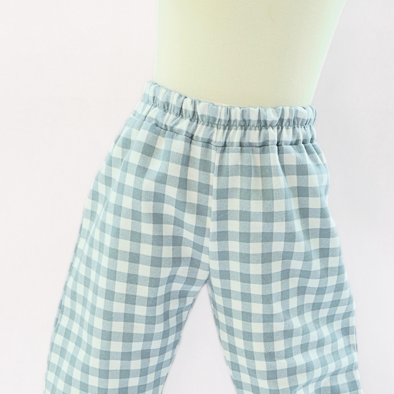 May include: Light blue and white gingham patterned pajama pants with an elastic waistband. The pants are made of a soft fabric and are designed for comfort. The classic check pattern is a timeless design.