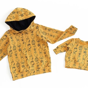 May include: Two mustard yellow hooded sweatshirts with a black and white animal print. The larger sweatshirt has a hood with a black lining.