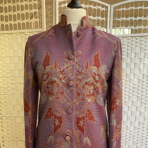 May include: A purple, red and gold floral patterned jacket with a mandarin collar and button closure.