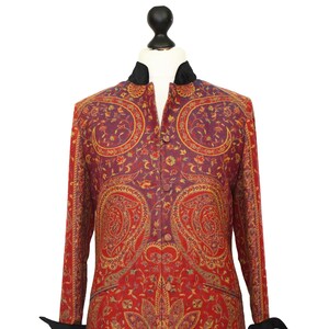 Op de afbeelding: Een lange rode en paarse jas met paisley-patroon, met een zwarte kraag en manchetten.