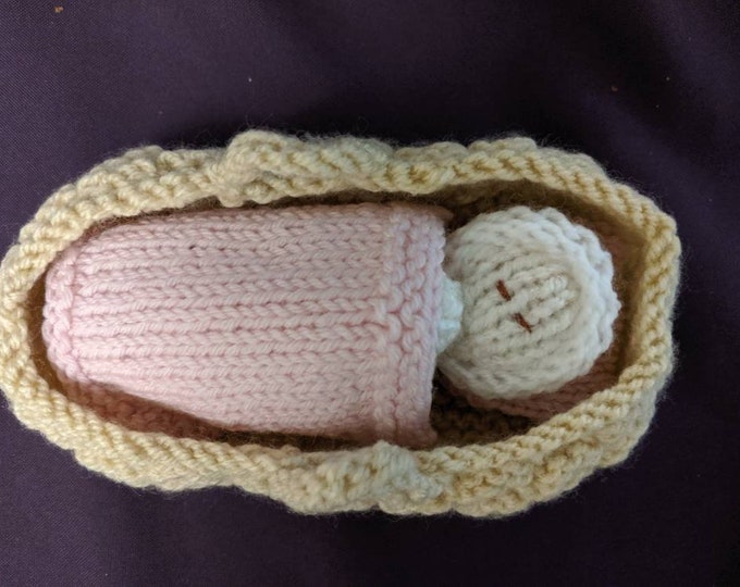 Baby and crib with pink blanket and pillow.