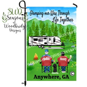 May include: A garden flag with a watercolor illustration of a camper van, two people sitting in chairs, and a dog. The text on the flag reads "Glamping our Way Through Life Together" and "Anywhere, GA".