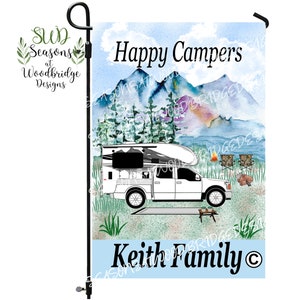 May include: A white pickup truck with a camper top is parked in front of a mountain scene. The words "Happy Campers" are above the truck. The name "Keith Family" is below the truck. A garden flag with a black pole.