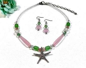 May include: A delicate necklace and earrings set featuring pink and green glass beads, a silver starfish pendant, and a clear beaded chain.