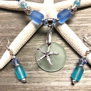 May include: A light blue sea glass necklace with a silver starfish pendant and matching earrings. The necklace features light blue sea glass beads and silver accents. The earrings are made with light blue sea glass beads and silver hooks.