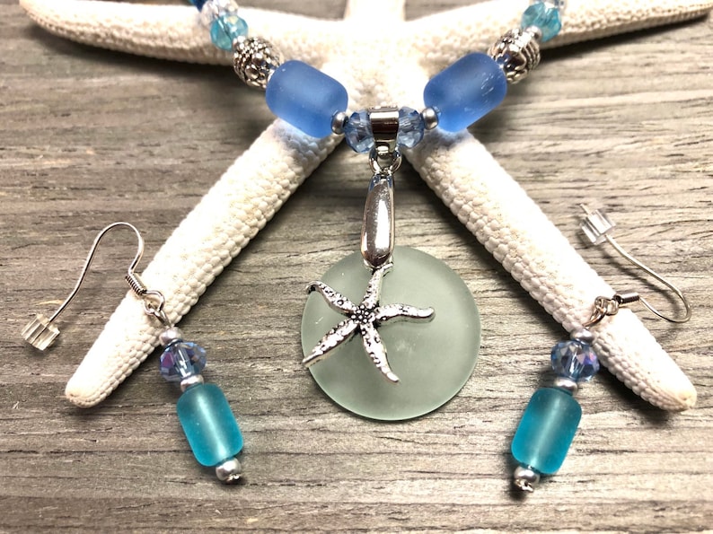 May include: A light blue sea glass necklace with a silver starfish pendant and matching earrings. The necklace features light blue sea glass beads and silver accents. The earrings are made with light blue sea glass beads and silver hooks.